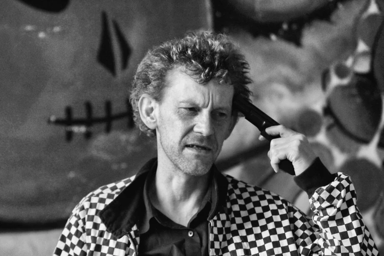 a man talking on the phone with hair drier and checkered jacket on