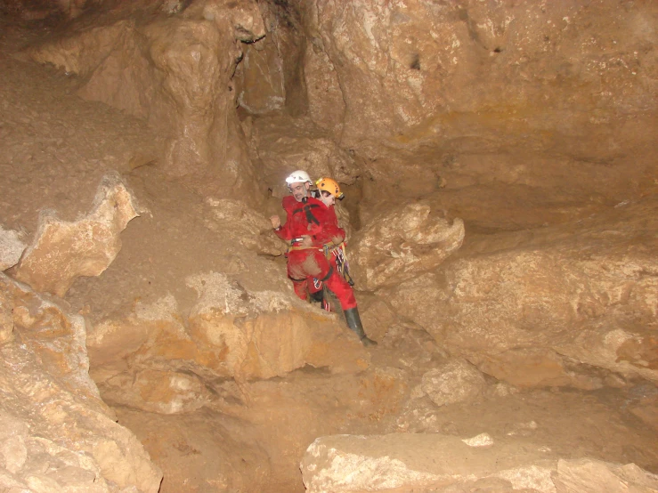 an adult in a red jacket standing inside a cave