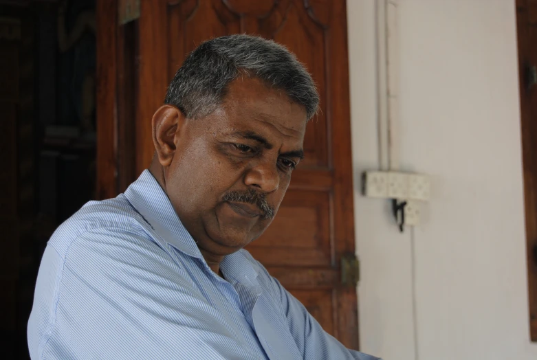 an indian man wearing a blue shirt and tie with a moustache
