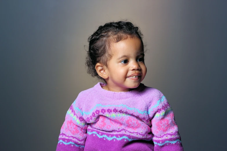 a little girl is wearing a purple sweater