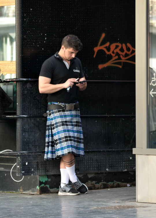 a man in a kilt looking at his cellphone