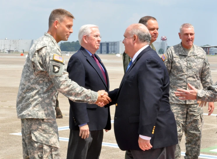 a group of men shaking hands on a tarmac