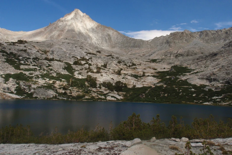 snow - covered mountains surrounding a lake surrounded by dry grass