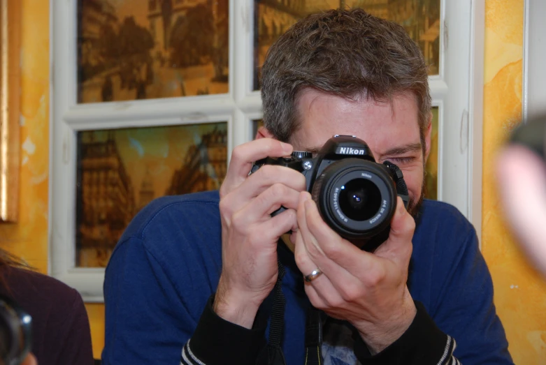 man taking po with camera and others looking at glass windows