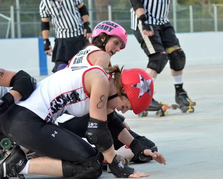 a women wearing pink helmet crouching next to another woman in black and white