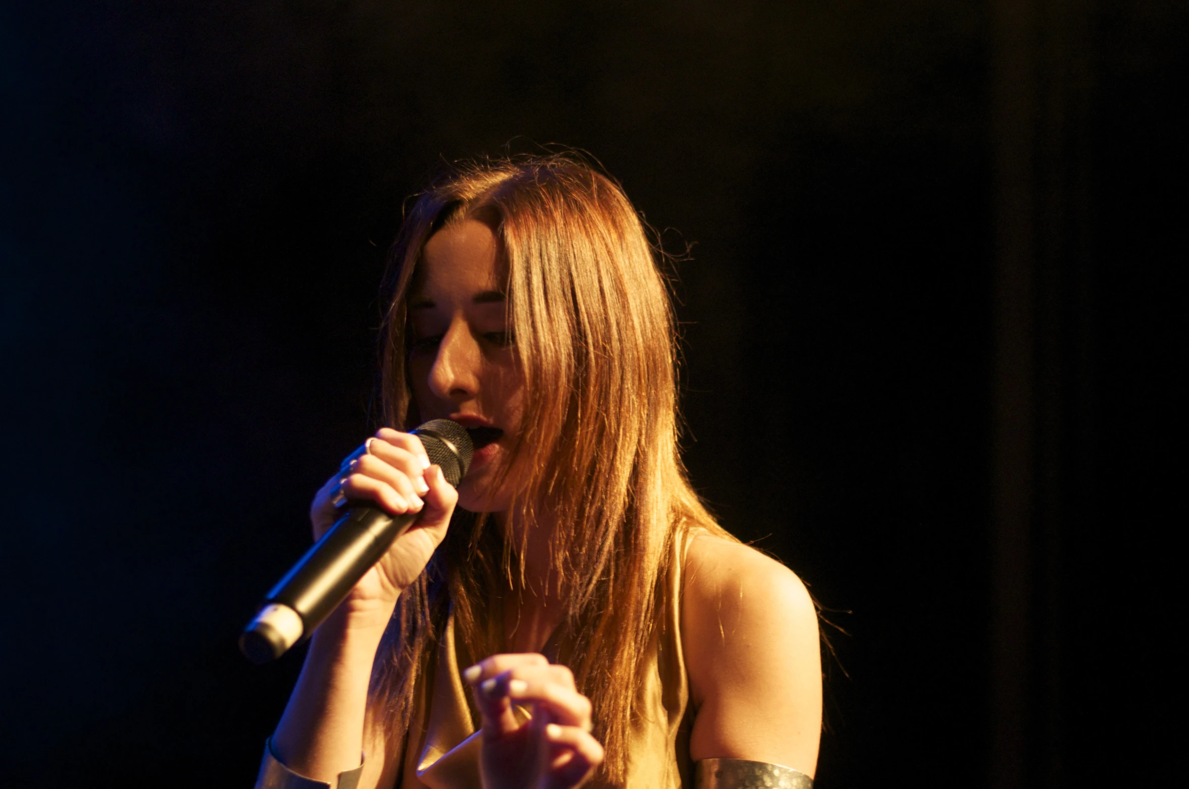 a woman on stage with her microphone up to the side