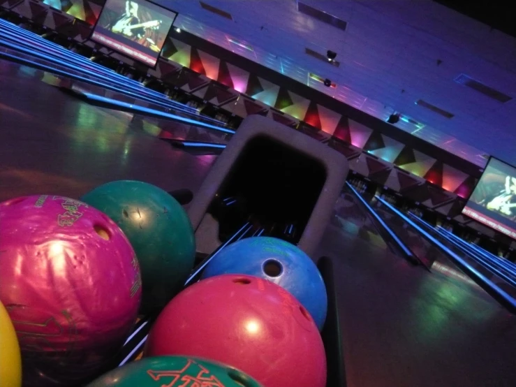 an indoor bowling alley that has a group of colorful balls next to them