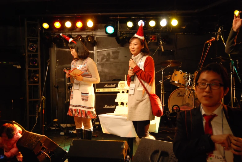 two s wearing christmas hats perform on stage