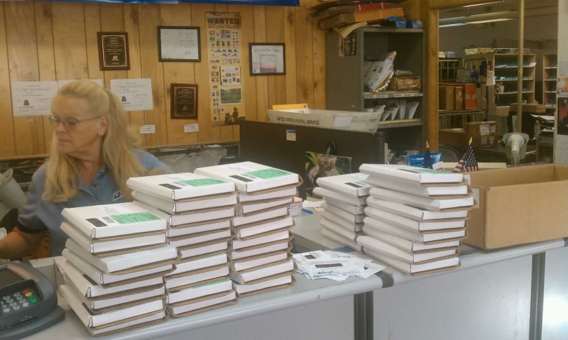 a woman in glasses is behind a large stack of white boxes