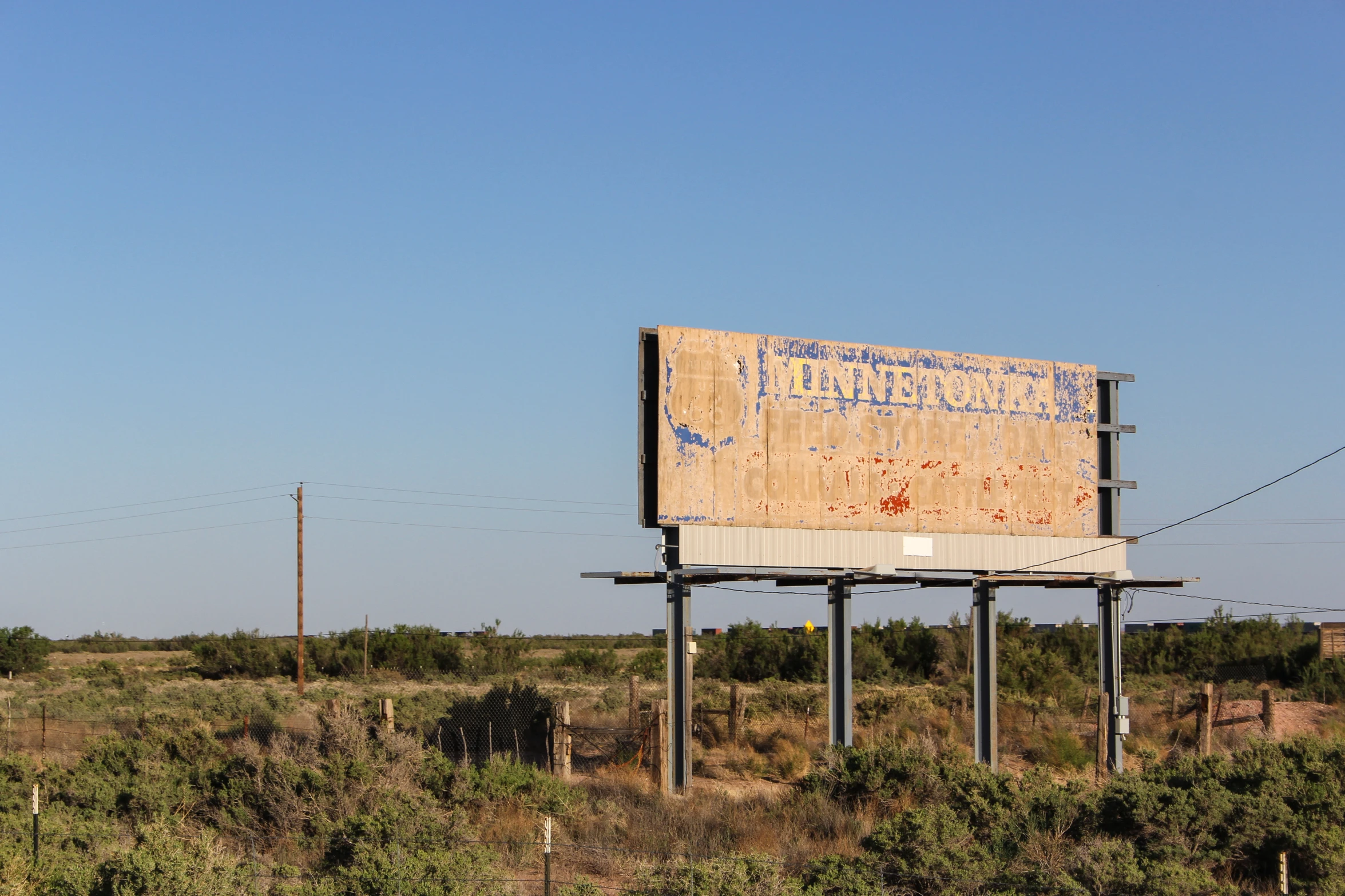 an old billboard in a field under blue skies