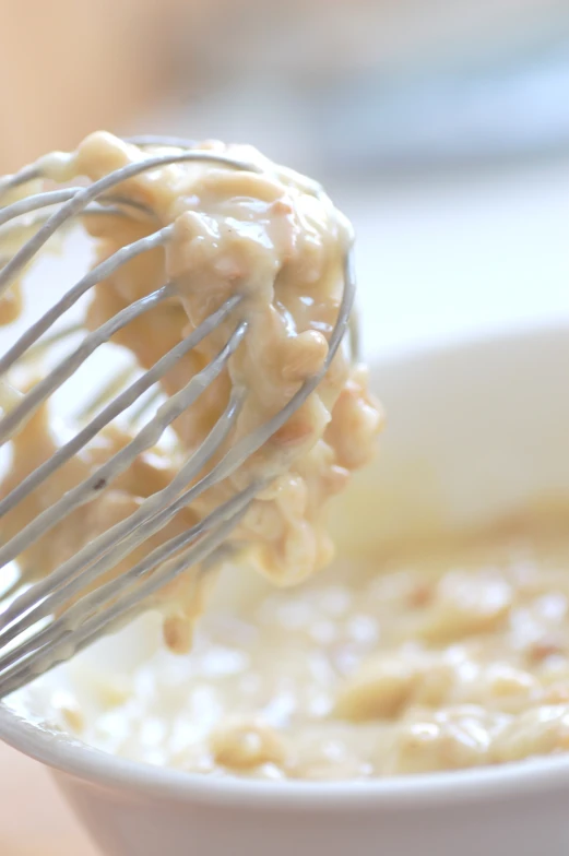 a white bowl full of cereal being stirred with a wire whisk