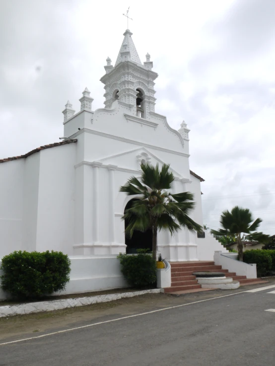 a building that is white and has a palm tree in front