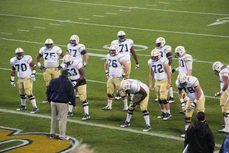 the football players are standing at the sidelines together