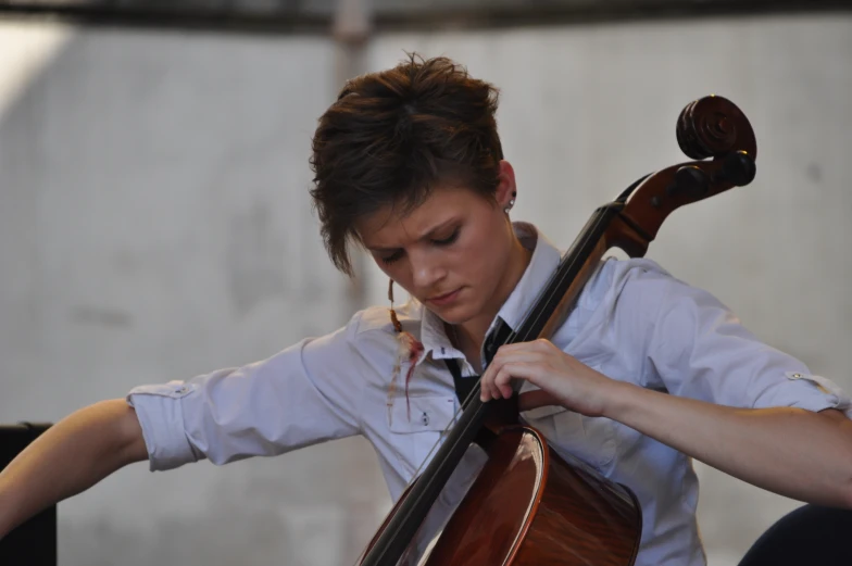 a young person with a tie around their neck is playing cello