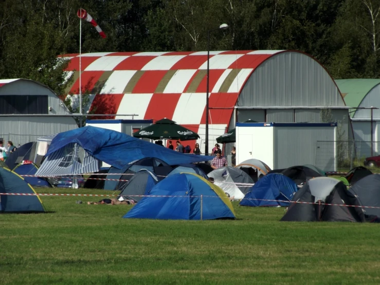 some tents and people in grassy area near a building