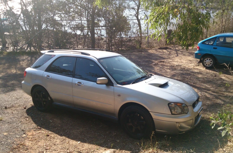 a white car parked in a driveway next to trees