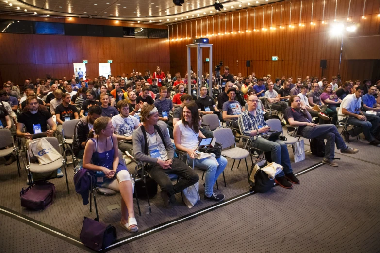 many people sitting in chairs looking at some speakers