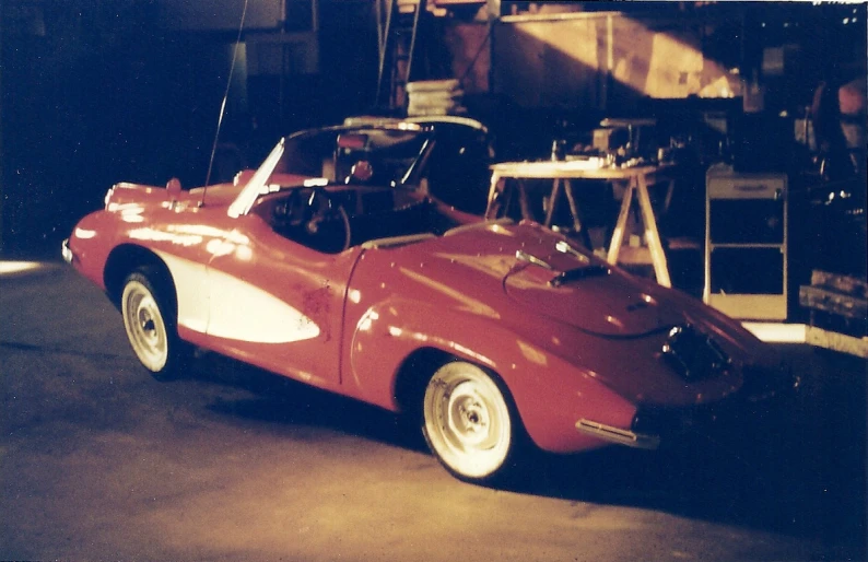 an old po of a red race car in an automobile garage