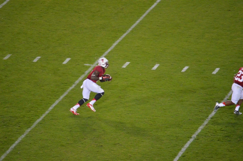 football players running on a field of green grass