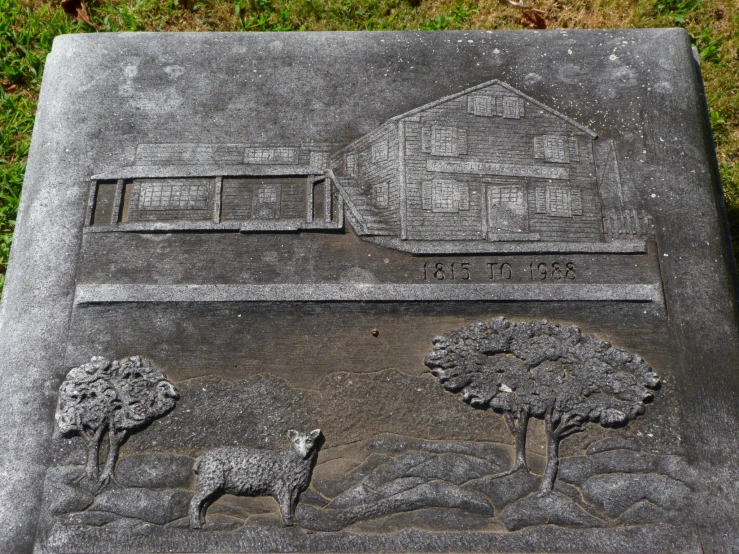 a stone carving of sheep and building in the background