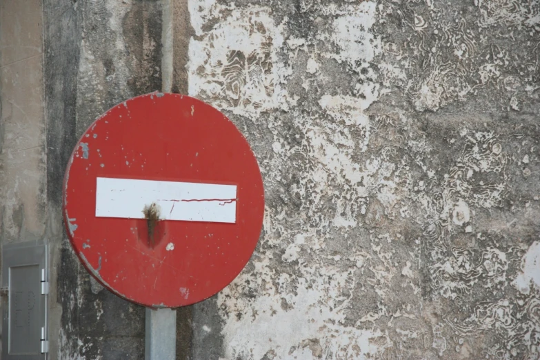 a red and white sign sitting in front of a cement wall