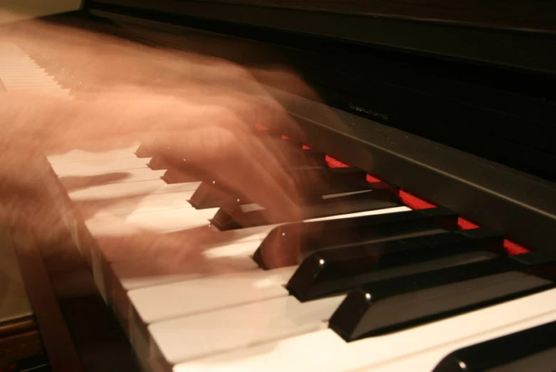 hands playing the piano keys in motion