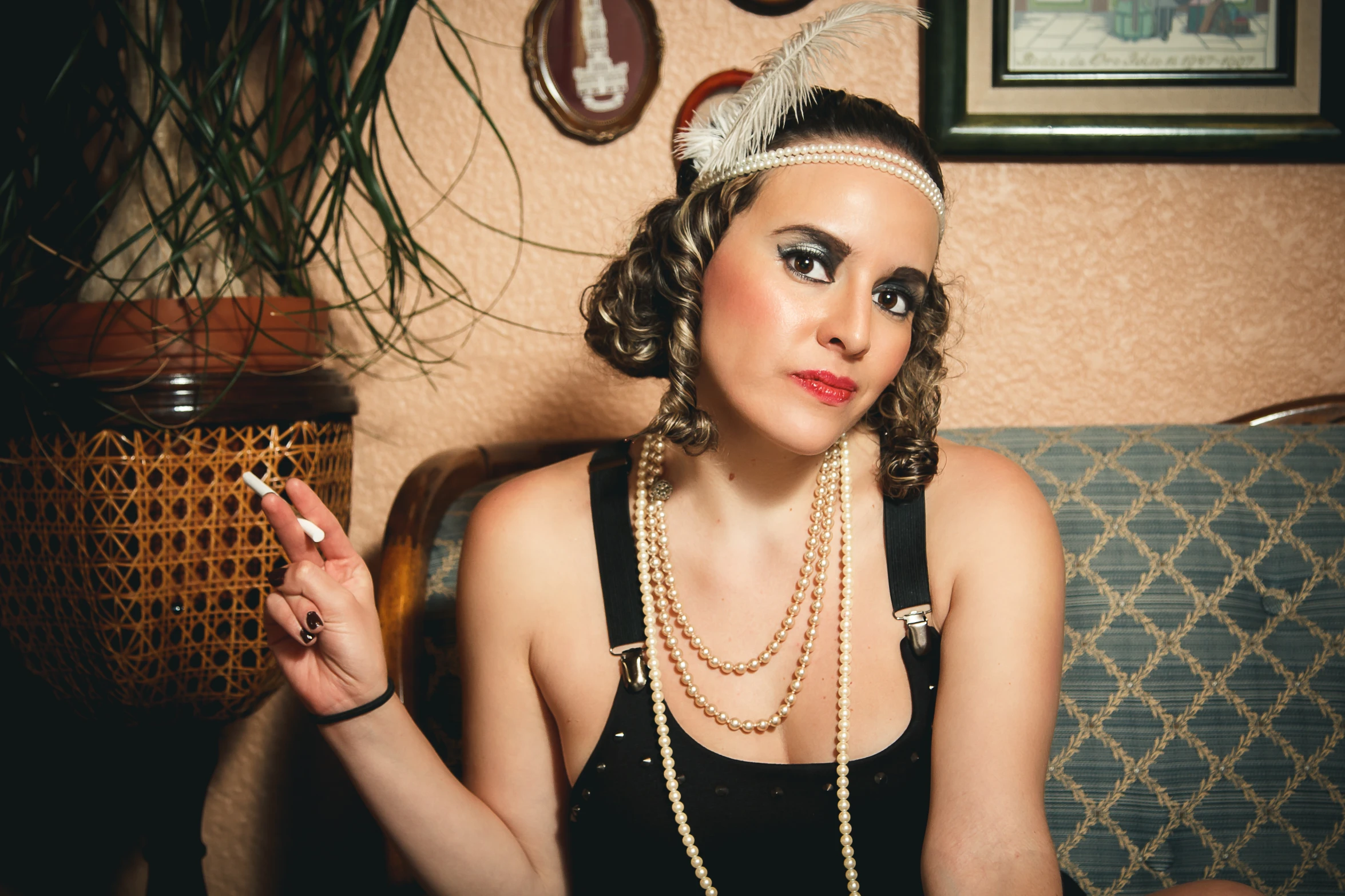 a woman in black sitting on a couch holding a cigarette