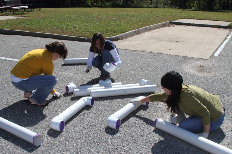 three girls building pipes with a stick