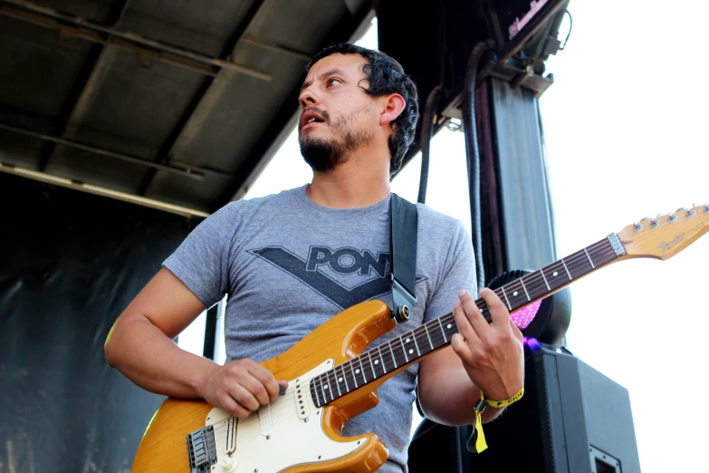 a man standing with an orange guitar and looking up at the sky