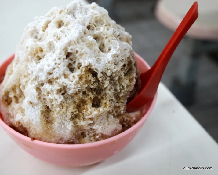 some type of ding in a pink bowl with a spoon