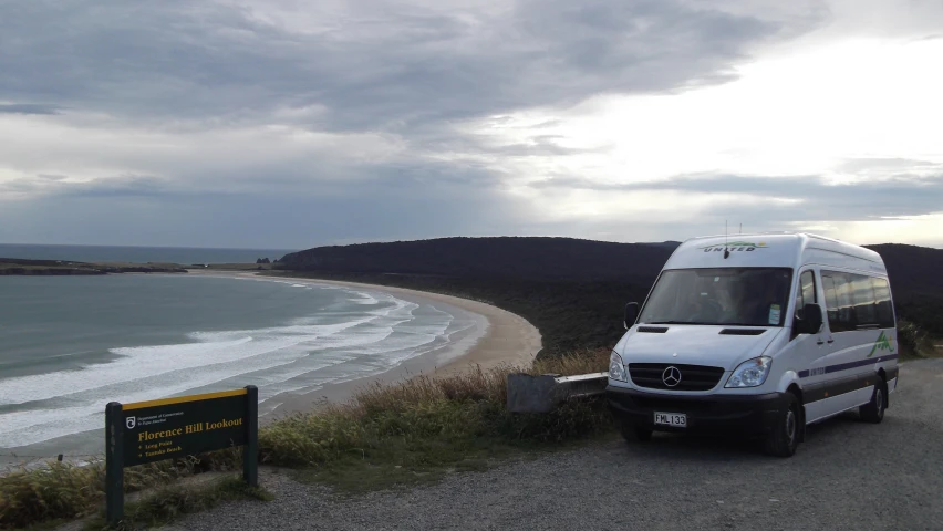 the van is parked on the side of the road by the beach