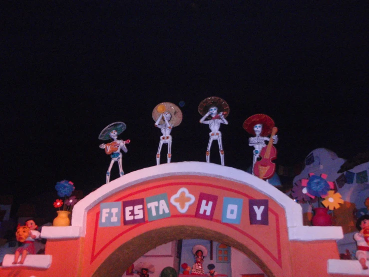 figurines on the top of the colorfully decorated arch of a toy store