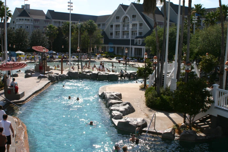 a pool in front of a resort and some people swimming