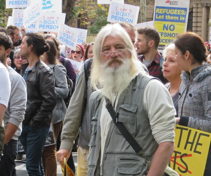 a large crowd of people stand behind a man with a long beard