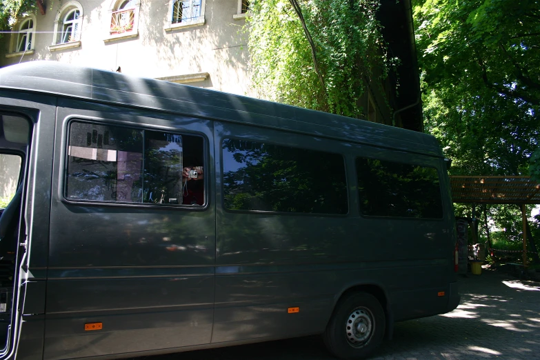 a large, green bus driving down a road in front of a building