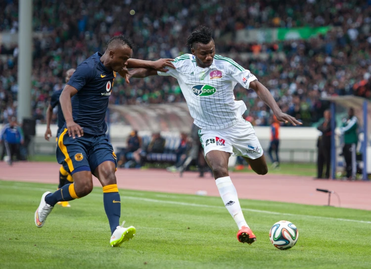 two young men kicking around a soccer ball on a field