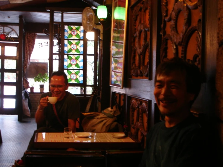 two men sitting in a restaurant talking on cell phones