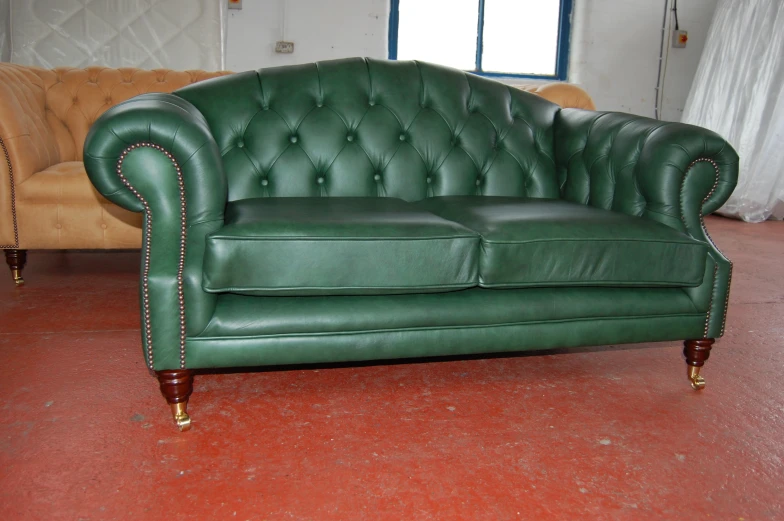 green leather couch in room with table and chairs