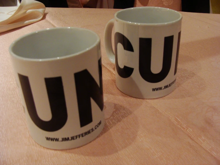 two coffee cups sitting on a table in front of some people