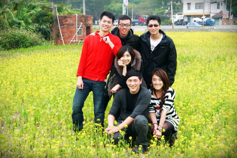 group of smiling men posing in field with one woman