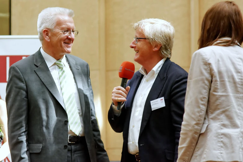 a man in a suit talking to an old lady on a microphone