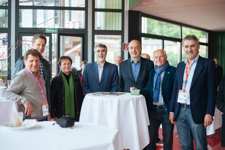 group of men and women stand in front of a table