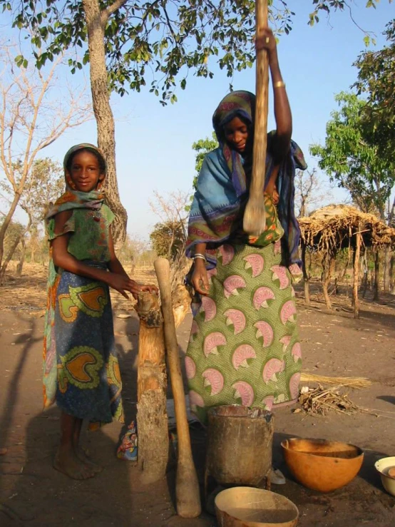 two young women standing next to each other near a tree