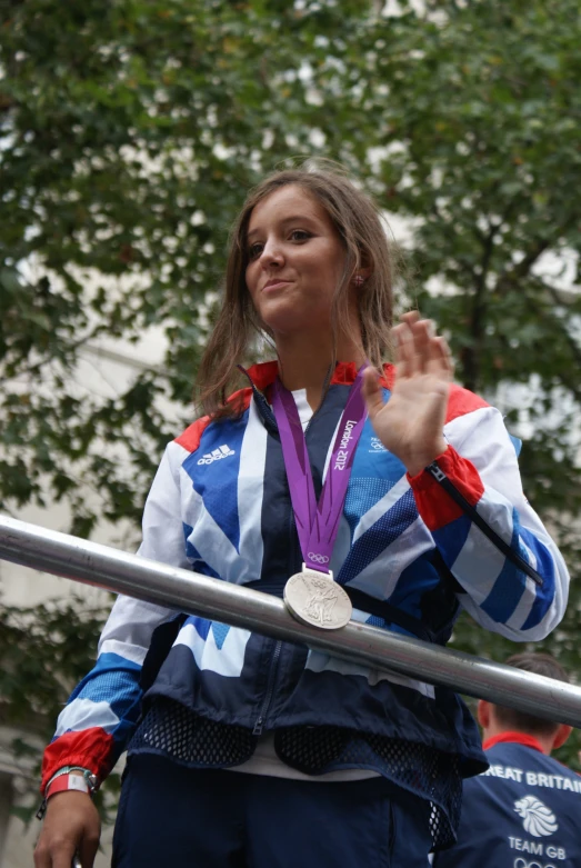 a woman in a track jacket with a silver medal on her hand