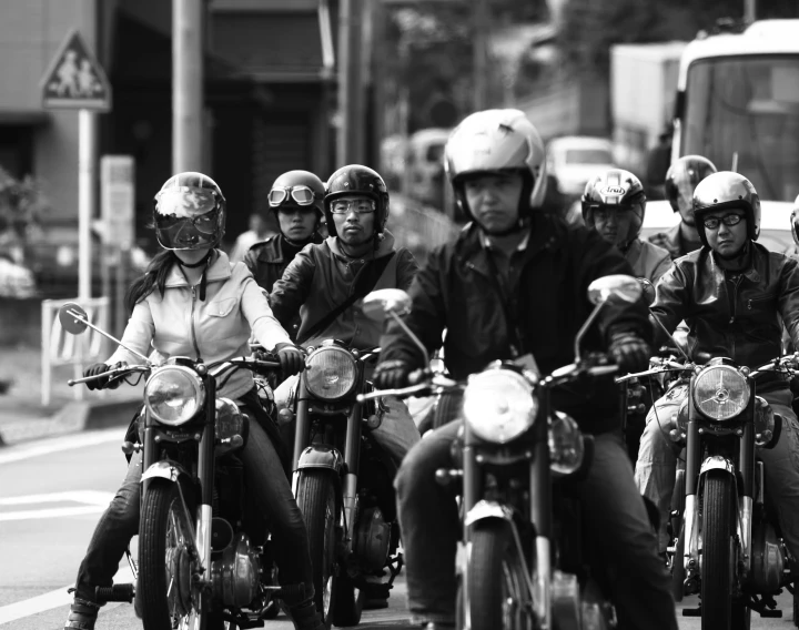 people riding motor cycles on the street wearing helmets