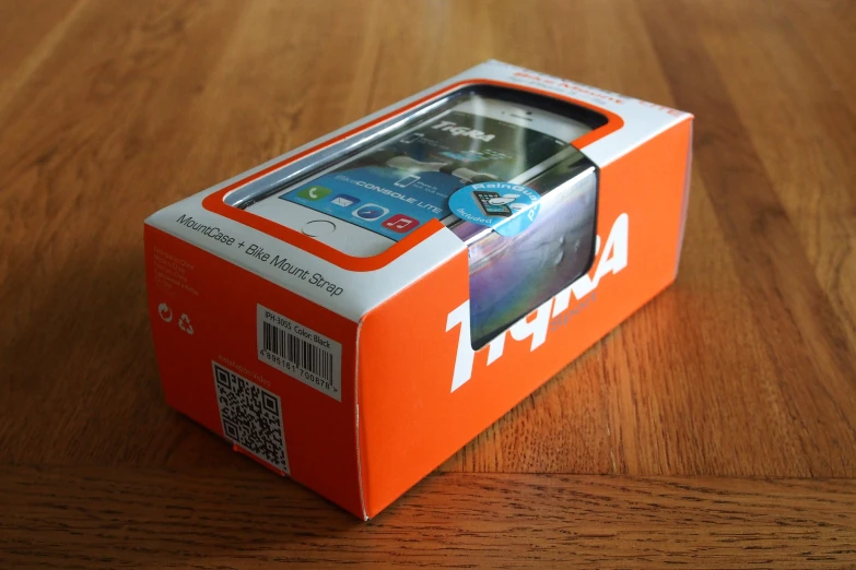 an orange box with a phone inside is shown on a wood table