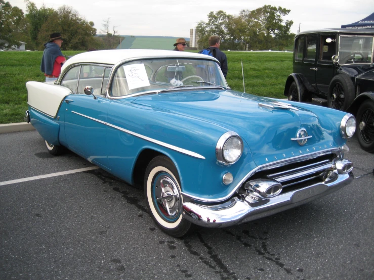 a couple of classic automobiles parked in a parking lot