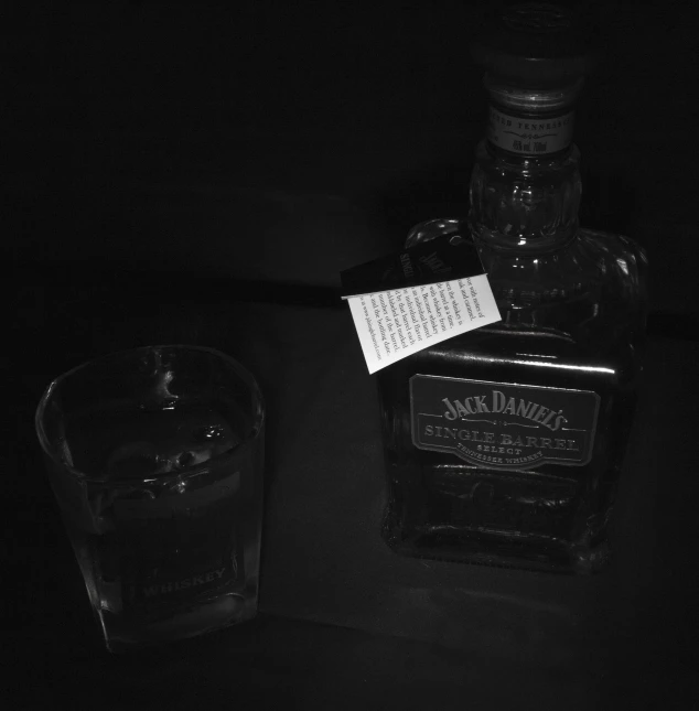 a bottle with a note sitting next to it next to a glass