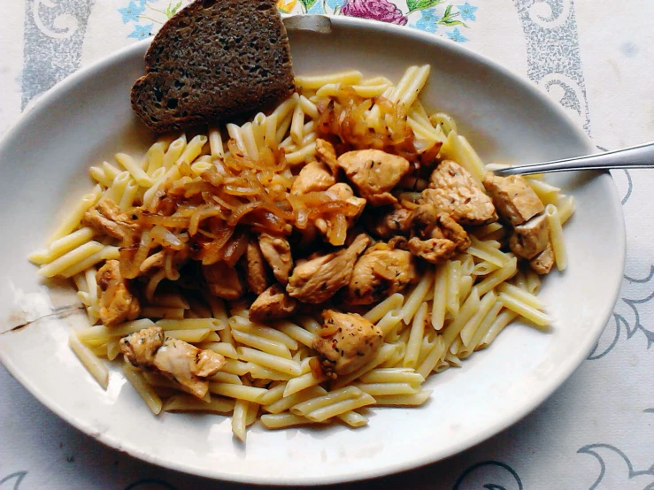 the plate is full of pasta, meat and bread