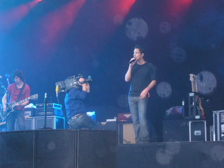three band members perform on a stage